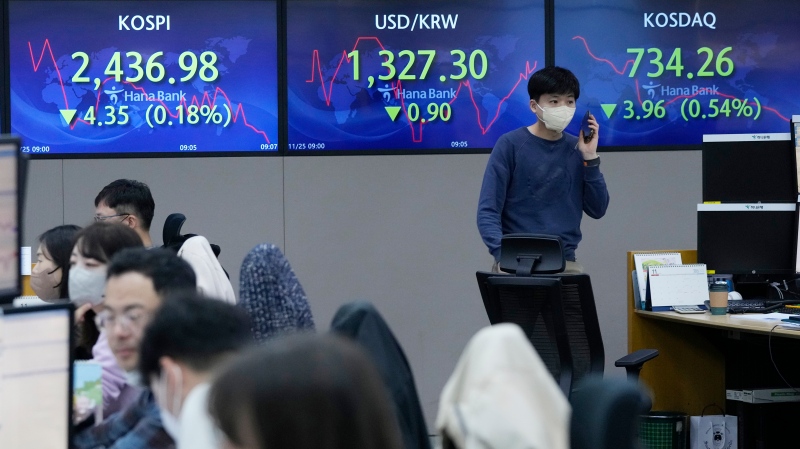 A currency trader passes by screens showing the Korea Composite Stock Price Index (KOSPI) at the foreign exchange dealing room of the KEB Hana Bank headquarters in Seoul, South Korea, Friday, Nov. 25, 2022. Asian shares were mixed Friday as worries deepened about the regional economy and Japan reported higher-than-expected inflation. (AP Photo/Ahn Young-joon)