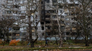 A woman walks past a recently damaged building due to a Russian strike in Kherson, southern Ukraine, Friday, Nov. 25, 2022. (AP Photo/Bernat Armangue)