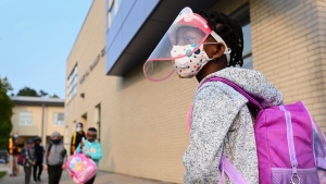 Five year-old Nancy Murphy wears a full mask and face shield as she waits in line for her kindergarten class to enter the school at Portage Trail Community School which is part of the Toronto District School Board (TDSB) during the COVID-19 pandemic in Toronto on Tuesday, September 15, 2020. THE CANADIAN PRESS/Nathan Denette