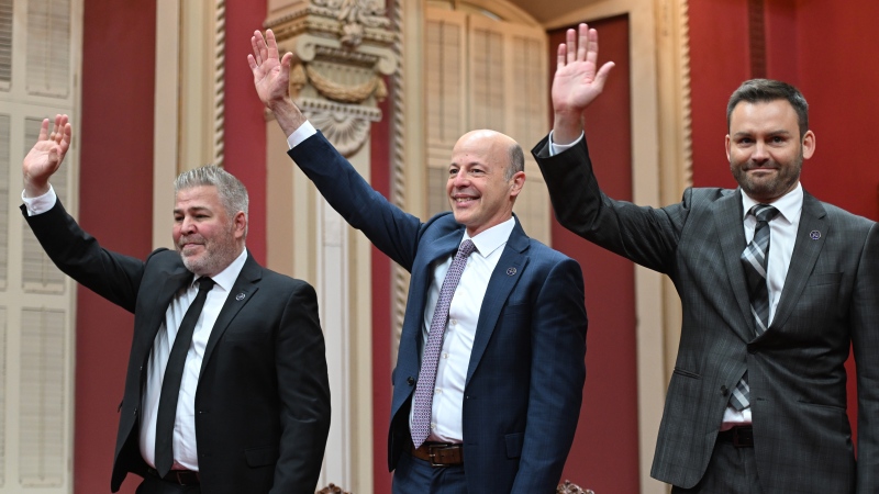 Parti Quebecois Leader Paul St-Pierre Plamondon, right, PQ MNAs Joel Arseneau, centre and Pascal Berube wave to the applauding supporters and family before being sworn in during a ceremony at the legislature in Quebec City, Friday, Oct. 21, 2022. THE CANADIAN PRESS / Jacques Boissinot