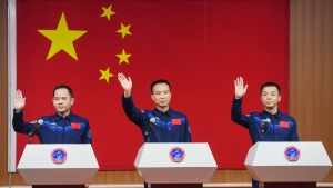 In this photo released by Xinhua News Agency, from left, Chinese astronauts for the upcoming Shenzhou-15 mission Zhang Lu, Fei Junlong and Deng Qingming wave during a meeting of the press at the Jiuquan Satellite Launch Center in northwest China, Nov. 28, 2022. (Liu Lei/Xinhua via AP)