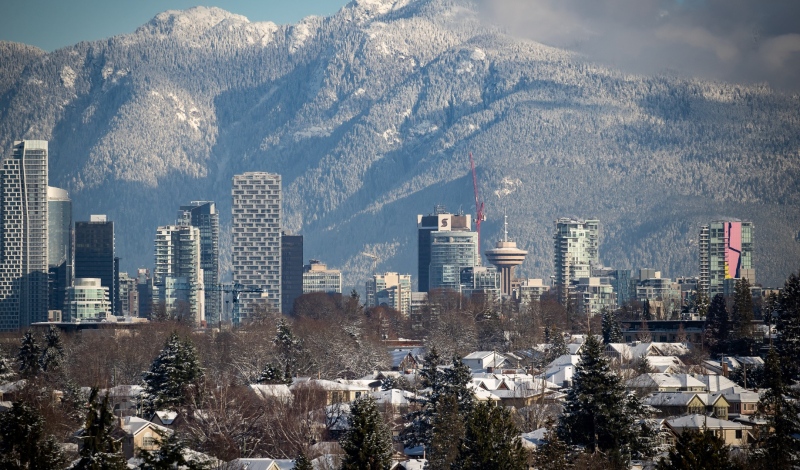 A file image shows snow-covered houses and the downtown skyline are seen with the north shore mountains in the distance in Vancouver. THE CANADIAN PRESS/Darryl Dyck