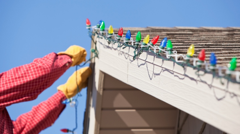 Christmas lights are pictured being hung on a house. (iStock)
