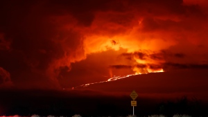 In this long camera exposure, cars drive down Saddle Road as Mauna Loa erupts in the distance, Monday, Nov. 28, 2022, near Hilo, Hawaii. Mauna Loa, the world's largest active volcano erupted Monday for the first time in 38 years. (AP Photo/Marco Garcia)