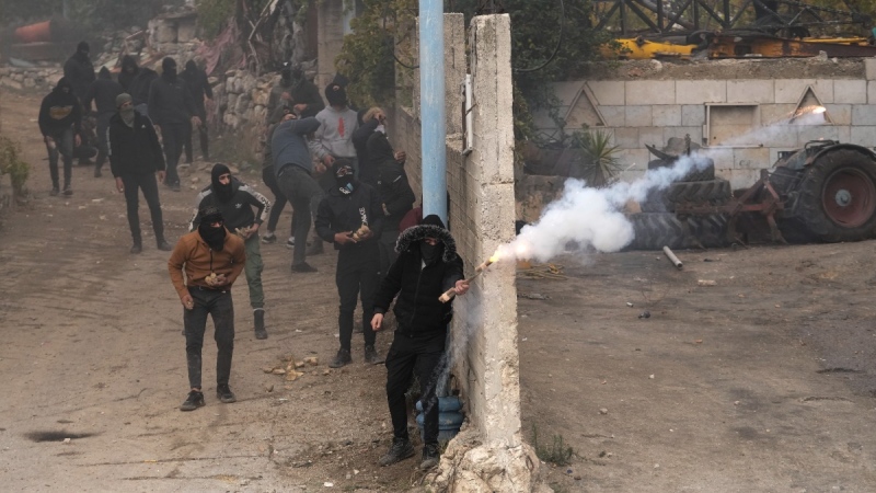 Masked Palestinians clash with Israeli security forces following the funeral of Mufid Khalil in the West Bank village of Beit Ummar, near Hebron, on Nov. 29, 2022. (Mahmoud Illean / AP) 