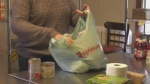 Food bank volunteer packs groceries into a plastic shopping bag. Nov. 29/22 (Amanda Hicks/CTV Northern Ontario)