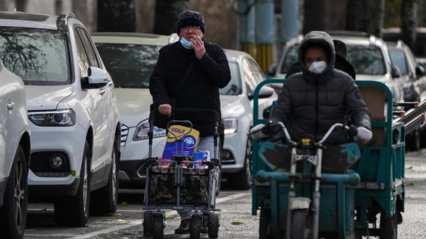 A man smokes while pushing a trolley loaded with groceries on a quiet street in Beijing, China, on Nov. 29, 2022. (Andy Wong / AP) 