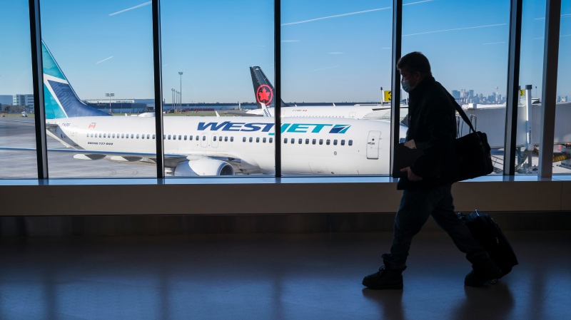 Passengers walk past Air Canada and WestJet planes at Calgary International Airport in Calgary, Alta., Wednesday, Aug. 31, 2022. The company has cancelled dozens of flights on Nov. 29 and 30, 2022 because of an incoming winter storm. THE CANADIAN PRESS/Jeff McIntosh