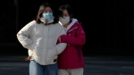 Women wearing face masks react to the freezing temperatures as they walk through a deserted street in Beijing, Tuesday, Nov. 29, 2022. Chinese universities are sending students home as the ruling Communist Party tightens anti-virus controls and tries to prevent more protests after crowds angered by its severe "zero COVID" restrictions called for President Xi Jinping to resign in the biggest show of public dissent in decades. (AP Photo/Andy Wong)