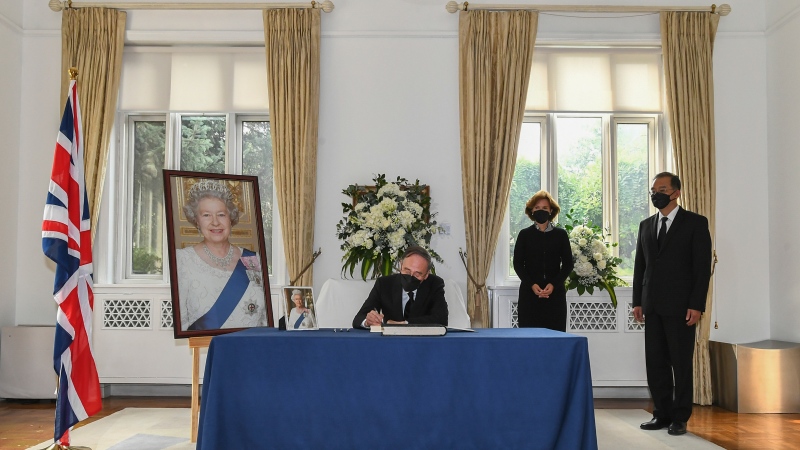 In this photo released by Xinhua News Agency, Chinese Vice President Wang Qishan, center, signs a condolence book next to British Ambassador to China Caroline Wilson, at the British Embassy in Beijing, Monday, Sept. 12, 2022. (Xie Huanchi/Xinhua via AP)