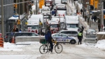 A cyclist stops in front of trucks blocked on Metcalfe Street as a rally against COVID-19 restrictions, which began as a cross-country convoy protesting a federal vaccine mandate for truckers, continues in Ottawa, Feb. 4, 2022. THE CANADIAN PRESS/ Patrick Doyle