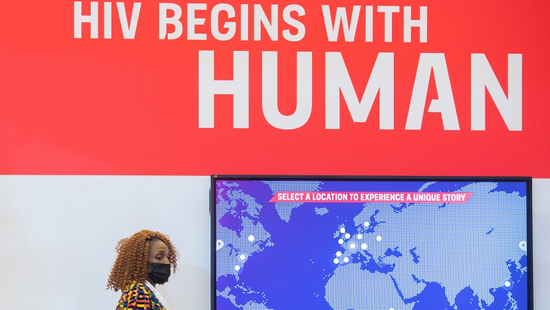 A woman walks by a sign during the AIDS 2022 conference in Montreal, July 31, 2022. THE CANADIAN PRESS/Graham Hughes