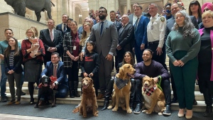 Manitoba politicians and several pet owners and their dogs pose for photos at the Manitoba legislature in Winnipeg on Tuesday, Nov. 29, 2022. The legislature has passed a bill that would people from leaving their pets unattended in vehicles in times of extreme weather. THE CANADIAN PRESS/Steve Lambert