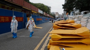 Workers in protective gear walk by dismantled barricades after authorities' easing of COVID-19 curbs in Haizhu district in Guangzhou in south China's Guangdong province, Dec. 2, 2022. (Chinatopix Via AP)