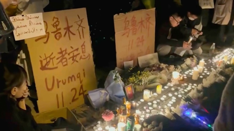 Residents light candles near a sign, which reads, "Urumqi, 11.24, Rest in Peace," in red, referring to the deadly apartment fire in China's western city of Urumqi that sparked anger over perceptions the country's strict COVID-19 measures played a role in the disaster during a vigil in Shanghai during the early hours of Nov 27, 2022. (AP Photo)