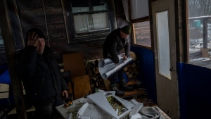 Two Ukrainian workers install thermal insulation in a small restaurant in Kyiv, Ukraine, Friday, Dec. 2, 2022. (AP Photo/Bernat Armangue)