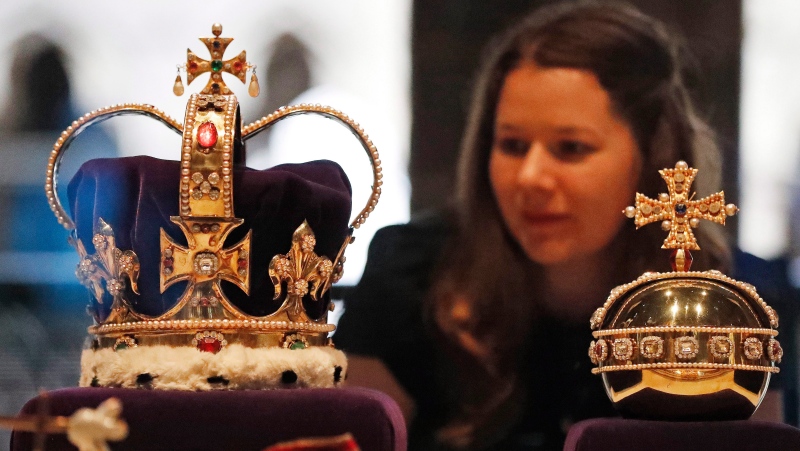 A woman looks at the St. Edward's Crown and Orb, part of an exhibition at the The Queen's Diamond Jubilee Galleries, in Westminster Abbey, in London, Tuesday, May 29, 2018. (AP Photo/Frank Augstein)