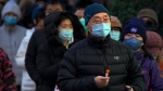 A man wearing a face mask holds his testing tube as masked residents line up for their routine COVID-19 throat swabs at a coronavirus testing site in Beijing on Dec. 4, 2022. China on Sunday reported two additional deaths from COVID-19 as some cities move cautiously to ease anti-pandemic restrictions amid increasingly vocal public frustration over the measures. (AP Photo/Andy Wong)