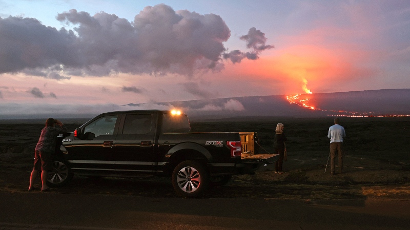 People stand on the side of the road to photograph the eruption of the Mauna Loa volcano on Dec. 4, near Hilo, Hawaii. (Justin Sullivan/Getty Images)
