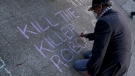 A man writes on the sidewalk while taking part in a demonstration about the use of robots by the San Francisco Police Department outside of City Hall in San Francisco, Monday, Dec. 5, 2022. (AP Photo/Jeff Chiu) 