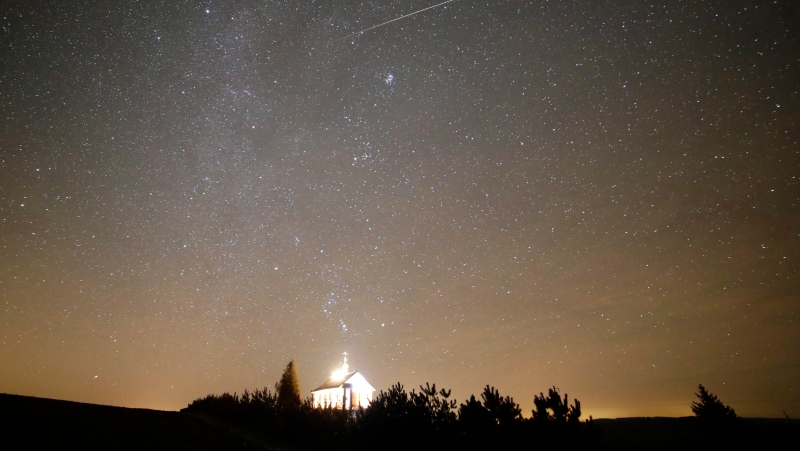A meteor streaks across the sky during the annual Geminids meteor shower over an Orthodox church on the local cemetery near the village of Zagorie, some 110 kilometres (69 miles) west of capital Minsk, Belarus, late Wednesday, Dec. 13, 2017. (AP Photo/Sergei Grits)