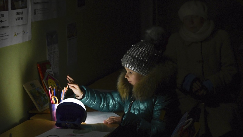 Alexandra, 11, draws at a school building, a 'Point of Invincibility,' a government-built help station that allows to charge phones with help of generators, serves food, drinks and the possibility to warm up, in Kramatorsk, Ukraine, Monday, Dec. 5, 2022. (AP Photo/Andriy Andriyenko)