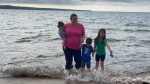 In this undated photograph provided by police, Susan French, in pink, stands with her children Deckard, left, Ryker, middle-right, and Emma, right, on a beach. (Source: RCMP)