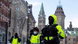 The Peace Tower is seen behind police at a gate along Queen Street as they restrict access to the streets around Parliament Hill to end to a protest, which started in opposition to mandatory COVID-19 vaccine mandates and grew into a broader anti-government demonstration and occupation, on its 23rd day, in Ottawa, Saturday, Feb. 19, 2022. THE CANADIAN PRESS/Justin Tang 
