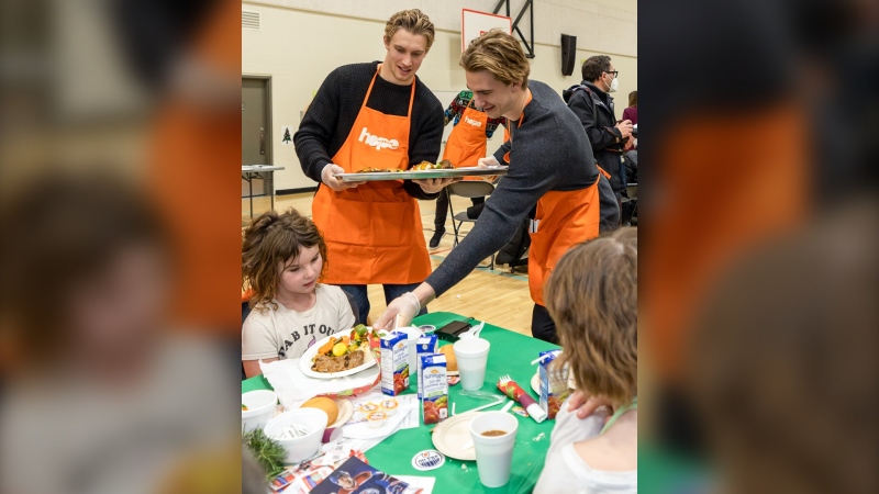 Dylan Holloway and Ryan McLeod serve food at the Hope Mission's annual Tegler Family Christmas Banquet at Ivor Dent School on Dec. 8, 2022. (Edmonton Oilers)


