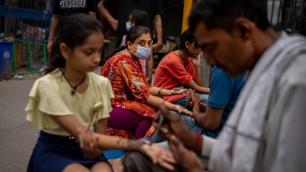 A woman wearing a mask as a precaution against COVID-19 gets her hands decorated with henna in New Delhi, India, on Aug. 11, 2022. (Altaf Qadri / AP) 