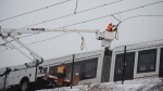 A worker repairs overhead wires on a stalled LRT OC Transpo train near Lees Ave., station in Ottawa, on Friday, Jan. 6, 2023. According to city officials freezing rain partially shut down train service between a number of station in the city’s east-end damaging overhead wires. (Spencer Colby/THE CANADIAN PRESS)