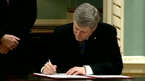 Prime Minister Stephen Harper signs a document after all the new cabinet members were sworn-in at Rideau Hall in Ottawa, Tuesday, Jan. 19, 2010.