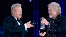 Robbie Bachman, left, videotapes a closeup as brother Randy Bachman holds the Juno trophy after they were both inducted into the Canadian Music Hall of Fame at the Juno Awards in Winnipeg, Sunday, March 30, 2014. THE CANADIAN PRESS/John Woods
