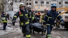 Rescue workers carry the body of a man who was killed in a Russian missile strike on an apartment building in the southeastern city of Dnipro, Ukraine, Monday, Jan. 16, 2023. (AP Photo/Evgeniy Maloletka) 