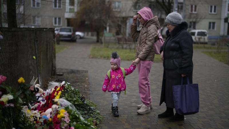 People pay their respects at the scene where a helicopter crashed into civil infrastructure on Wednesday, in Brovary, on the outskirts of Kyiv, Ukraine, Friday, Jan. 20, 2023. (AP Photo/Daniel Cole)
