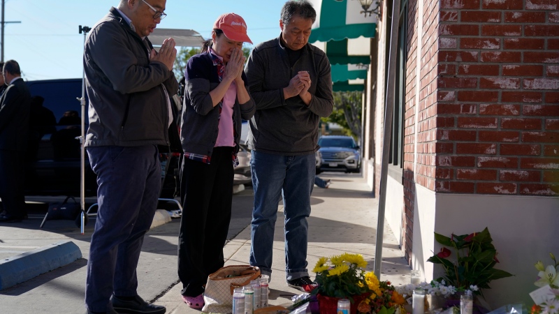 People pause at a memorial outside the Star Ballroom Dance Studio on Monday, Jan. 23, 2023, in Monterey Park, Calif. A gunman killed multiple people at the ballroom dance studio late Saturday amid Lunar New Year's celebrations in the predominantly Asian American community. (AP Photo/Ashley Landis) 