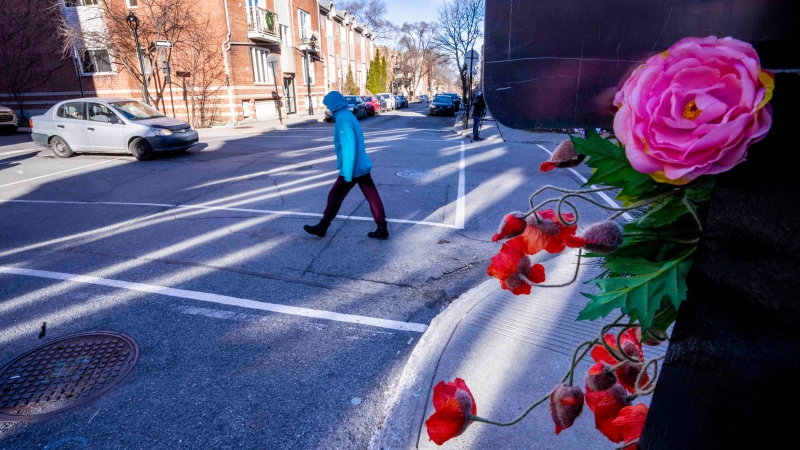 A pedestrian crosses the street on the corner where a seven-year-old girl was killed in a hit and run Tuesday, in Montreal, on Wednesday, December 14, 2022. THE CANADIAN PRESS/Paul Chiasson