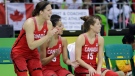 Twin Canada forwards Katherine Plouffe, left, and Michelle Plouffe, right, watch from the bench with guard Kia Nurse during the second half of a women's basketball game against Senegal at the Youth Center at the 2016 Summer Olympics in Rio de Janeiro, Brazil, Wednesday, Aug. 10, 2016. The Plouffe twins have helped Canada advance to the quarterfinals looking for the country's first medal in its sixth Olympics. Canada (3-0) will play the United States (3-0) in group play Friday in a good test of those Canadian medal hopes. (AP Photo/Carlos Osorio)