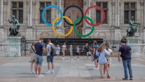 People gather at the Olympic rings at the City Hall in Paris, Monday, July 25, 2022. (AP Photo/Lewis Joly) 