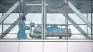 A health-care worker pushes a patient across a connecting bridge at a hospital in Montreal, Thursday, July 14, 2022, as the COVID-19 pandemic continues in the province. THE CANADIAN PRESS/Graham Hughes