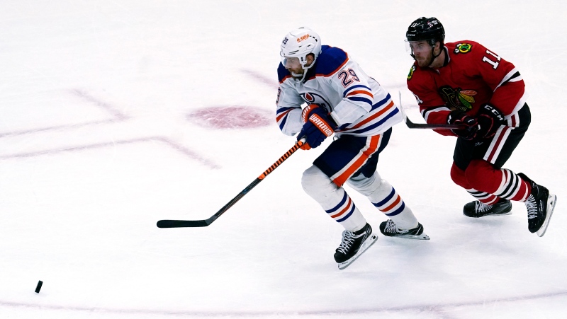 Edmonton Oilers center Leon Draisaitl, left, and Chicago Blackhawks right wing Taylor Raddysh chase the puck during the second period of an NHL hockey game in Chicago, Thursday, Oct. 27, 2022. (AP Photo/Nam Y. Huh)