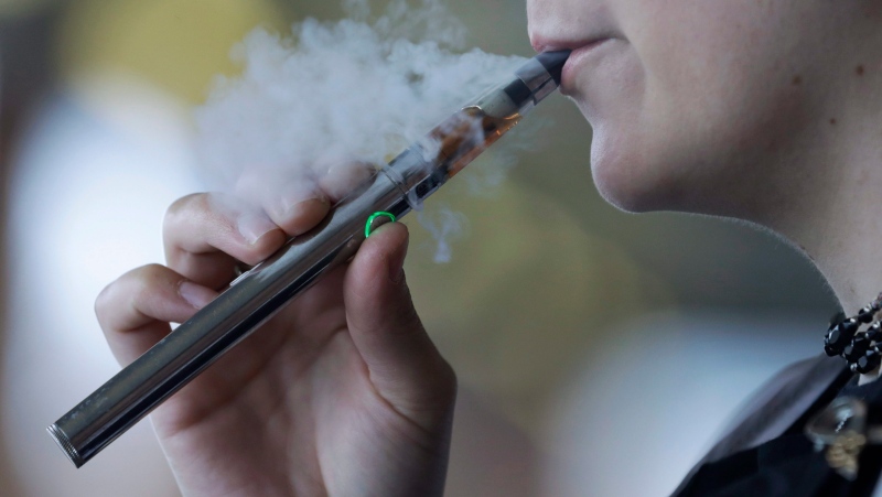 In this Friday, Oct. 4, 2019 photo, a woman using an electronic cigarette exhales in Mayfield Heights, Ohio. (AP Photo/Tony Dejak)