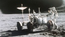 In this 1971 photo made available by NASA, astronaut James Irwin stands next to a rover on the surface of the moon.