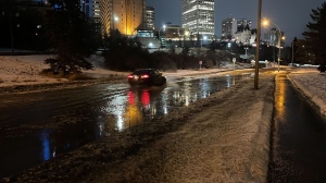 A car navigates through a stream of water in the Rossdale Road area (CTV News Edmonton/Sean McClune).