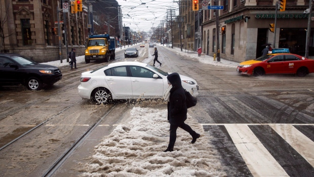 A pedestrian nearly misses getting splashed by a passing car in Toronto. THE CANADIAN PRESS/Cole Burston