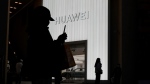 Shoppers are silhouetted outside a Huawei retail store in Beijing, Friday, Dec. 30, 2022. (AP Photo/Ng Han Guan) 