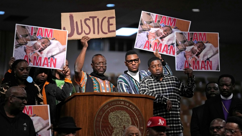 People hold signs during a news conference discussing the death of Tyre Nichols, Tuesday, Jan. 31, 2023, in Memphis, Tenn. (AP Photo/Jeff Roberson)