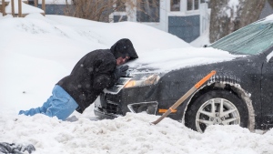 Mike Bolduc struggles to push a car out of his neighbour's driveway in Lewiston, Maine, on Feb. 4, 2022.  (Russ Dillingham / Sun Journal via AP) 
