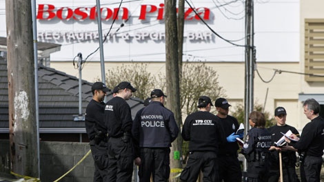 Police officers gather in a nearby alley as they search for evidence following a fatal shooting outside a Boston Pizza restaurant at Grandview Hwy. and Bentall St. in Vancouver, B.C., on Sunday April 5, 2009. (THE CANADIAN PRESS/Darryl Dyck)