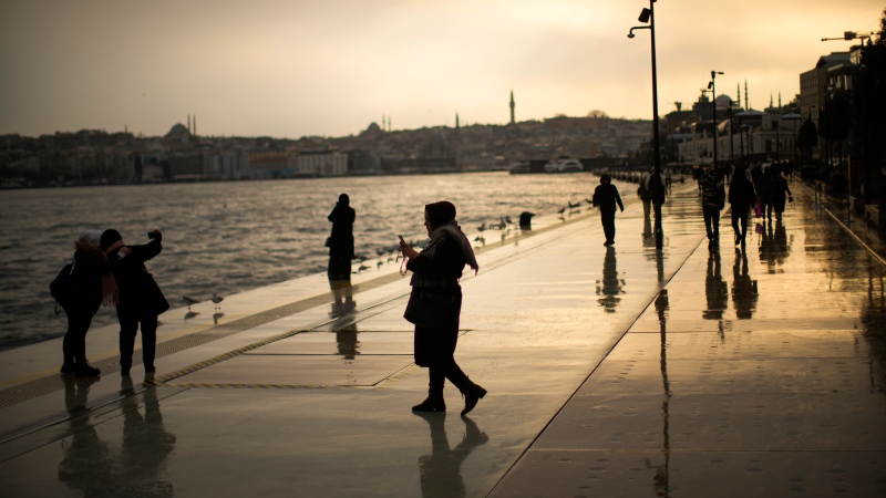 People walk along Galataport sea promenade in Istanbul, Turkey, Wednesday, Feb. 1, 2023. (AP Photo/Francisco Seco)